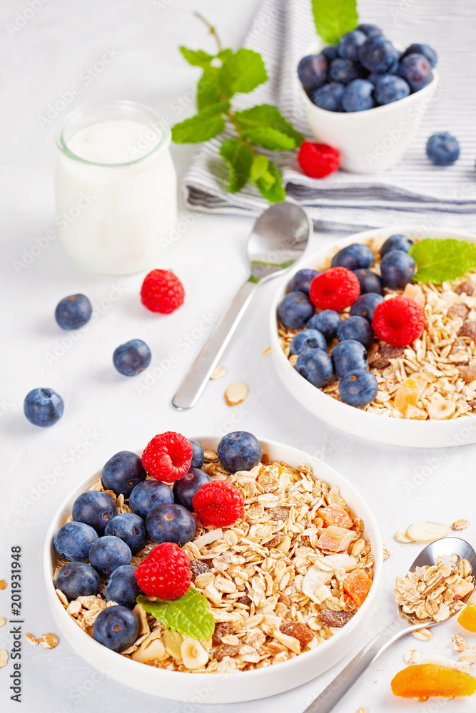 Homemade granola or oatmeal muesli with nuts, dried fruits and fresh berries. Healty diet breakfast, vegeterian food concept Homemade granola or oatmeal muesli with nuts, dried fruits and fresh berries. Healty diet breakfast, vegeterian food concept