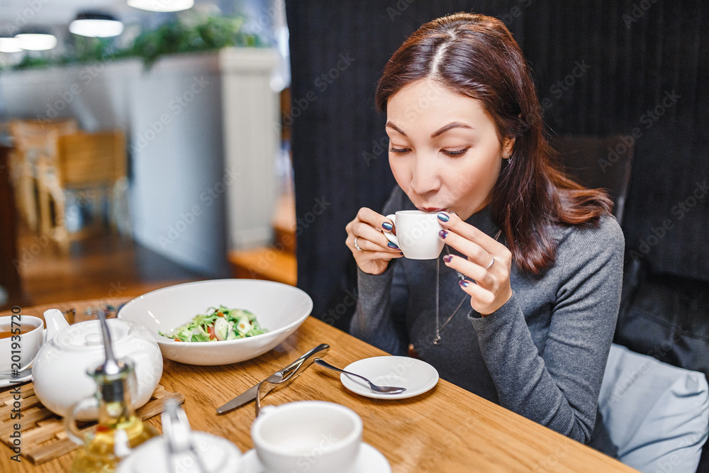 Young eastern woman drinking strong aroma coffee in a cafe Young eastern woman drinking strong aroma coffee in a cafe