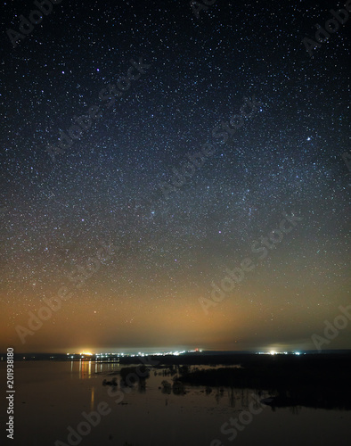 Night sky with stars above the river during the spring flood. View of the starry space.