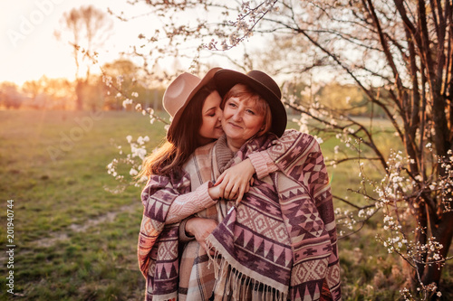 Middle-aged mother and her adult daughter hugging in blooming garden. Mother's day concept. Family values