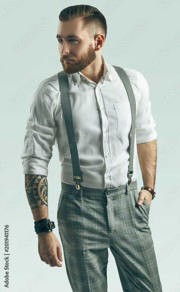 Brutal elegant man in gray classic pants and suspenders isolated on white  Photos | Adobe Stock