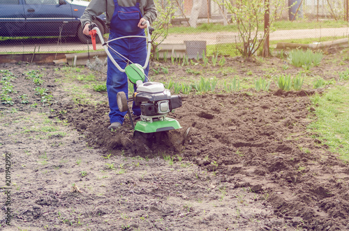 Man working in the spring garden with tiller machine