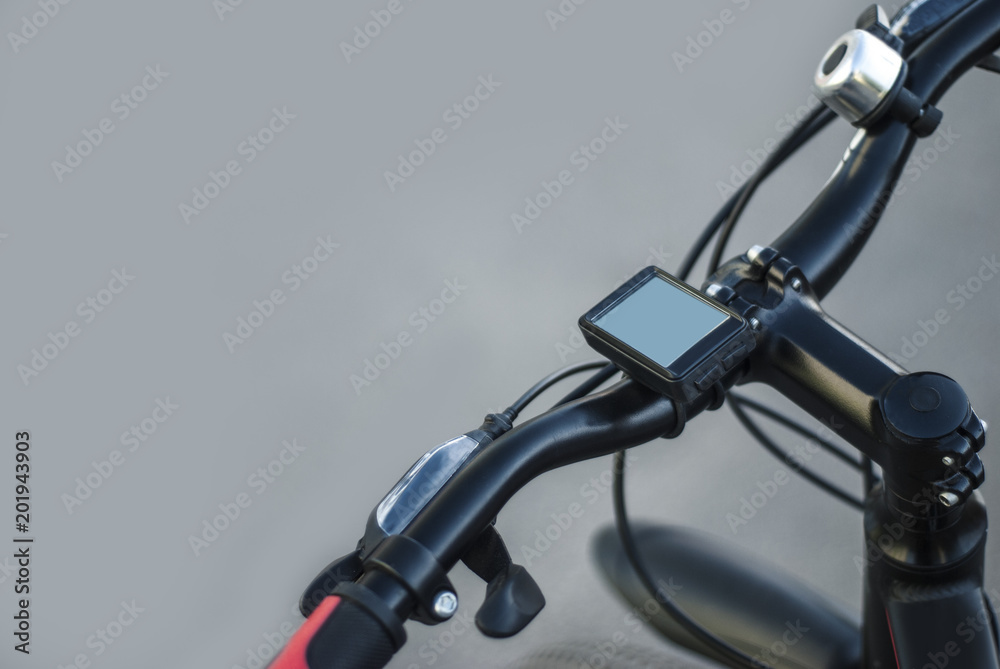 A mountain bike handlebar with a speedometer and a bell with bicycle hand brake on a gray background