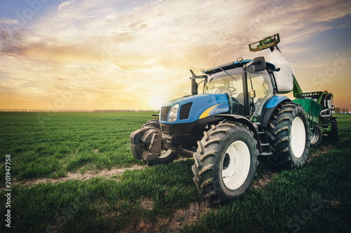 a tractor with a sack of fertilizer moves along the field in the spring photo