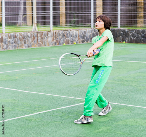 handsome boy in green sports suit, playing tennis