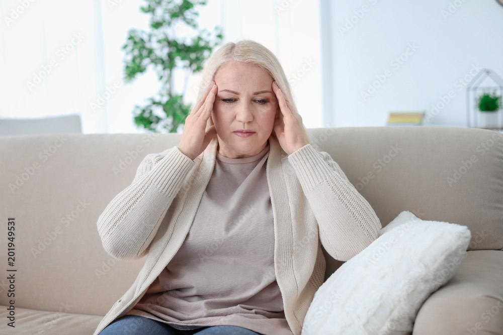 Mature woman suffering from headache while sitting on sofa at home Mature woman suffering from headache while sitting on sofa at home