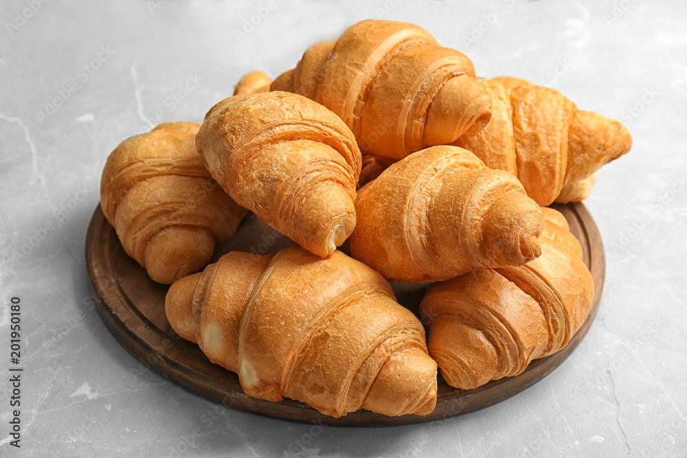 Wooden board with tasty croissants on table