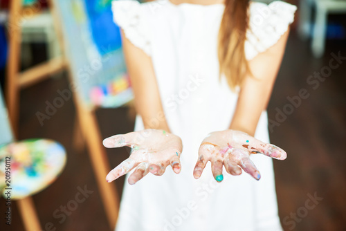 Close up of unrecognizable teenage girl showing hands smudged in paint at camera, copy space