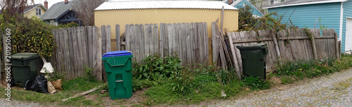 Vászonkép Unsightly ramshackle derelict fence seen in alley with debris and trash cans