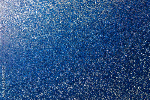 Blue metallic surface covered with water droplets