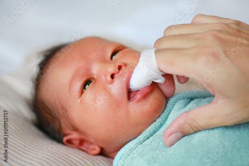 Mother use finger to clean baby tongue and gum with the clean gauze.