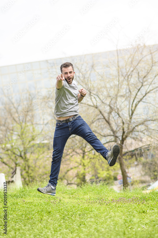 Victorious young man jumping in the air, celebrating freedom, feeling euphoria and exhilaration, shouting yes to life
