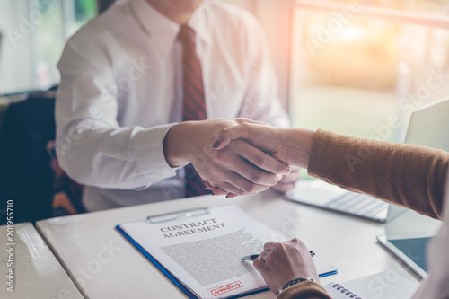 Two business shaking hands to each other above signed contract at meeting or negotiation in the office.