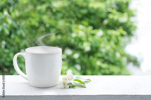 Cup of coffee on balcony in morning time with white flowers