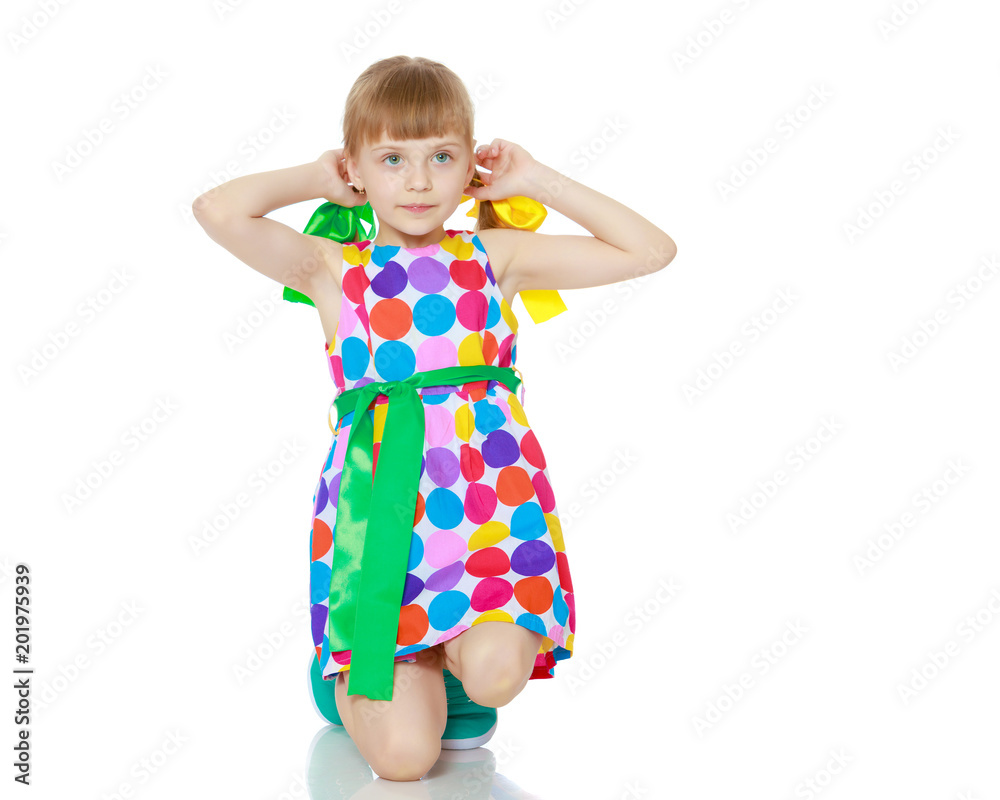 A little girl in a dress with a pattern from multi-colored circl A little girl in a dress with a pattern from multi-colored circl