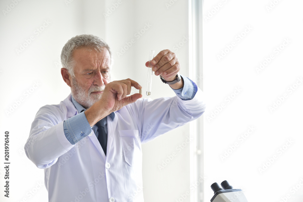 Obraz premium Senior male scientist holding a pill.