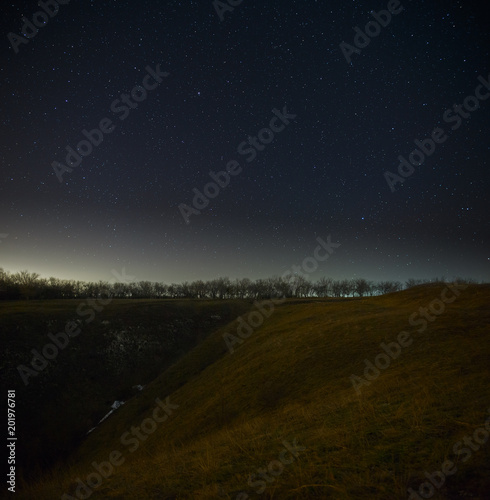 Bright stars in the night sky, forests and hills background. Landscape with a long exposure.