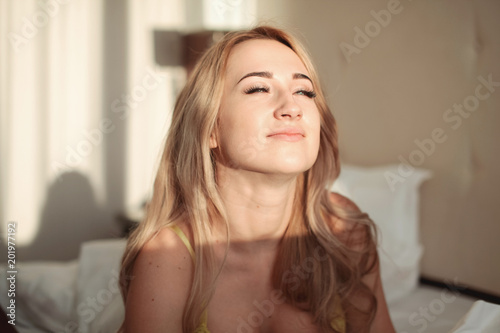 Pretty young woman on bed in modern apartment smiling after wake up © Kseniia