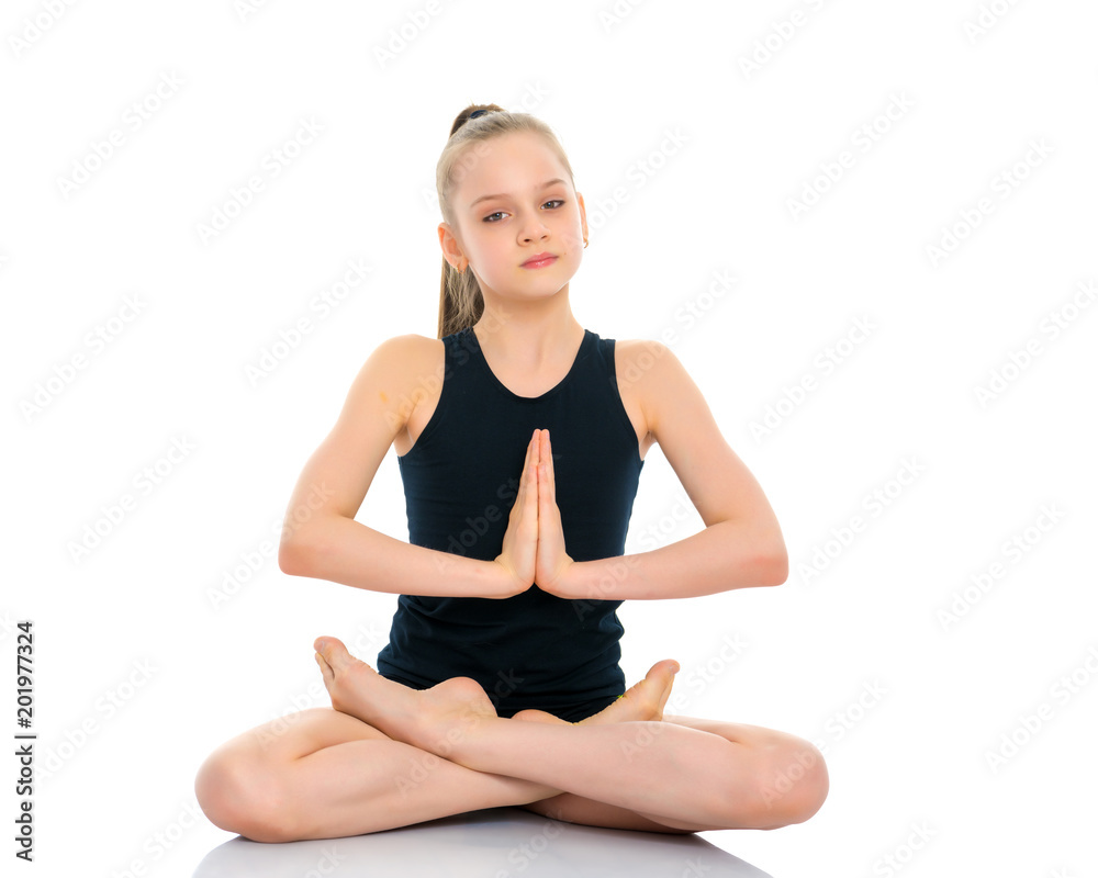 A little girl is meditating in a lotus pose.