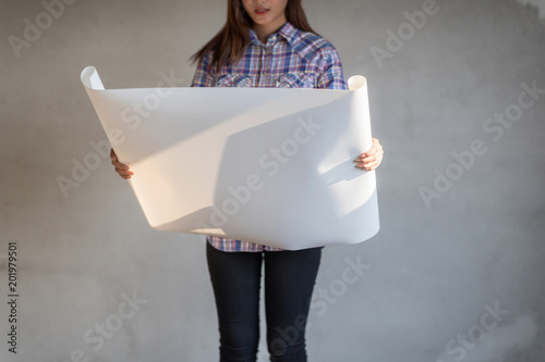 Beautiful young Asian engineer or technician woman smiling with white helmat and holding plans. photo