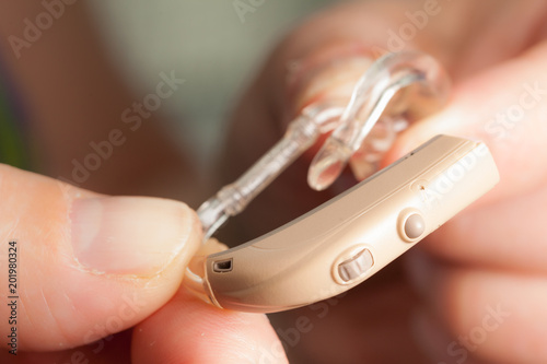 senior person holding hearing aid closeup
