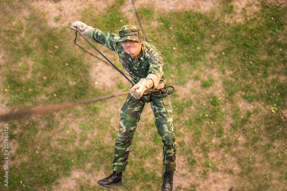 Soldier training rappel with rope. Military man does hanging on climbing  equipment. Stock Photo