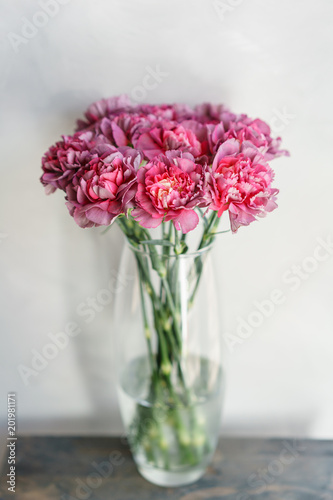 beautiful carnation flowers in a vase on a table . Bouquet of violet  purple and pink multicolor flower. Decoration of home. Wallpaper and background. Vertical photo