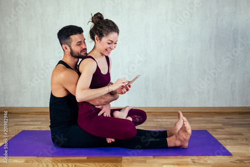 beautiful and young woman with curly hair and a sexy man doing selfie on yoga mat in floor. the concept of yoga in a pair and tantric yoga photo