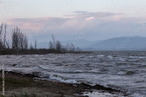 Moody lake shore at dusk, with waves and some warm sunset colors in the sky