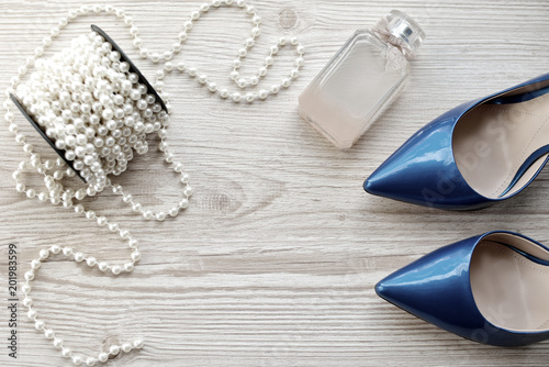 Blue shoes, perfume and beads on the table. Concept of femininity and beauty