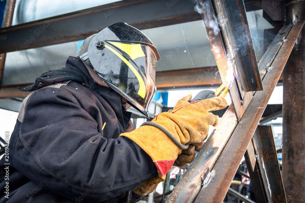 Worker in overalls mounts a metal structure.