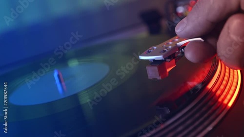 Vinyl player turntable. Defocus in the focus of the fragment of the rotating vinyl plate, the man's hand put the stylus with the needle on the vinyl close-up. Macro. Foreground