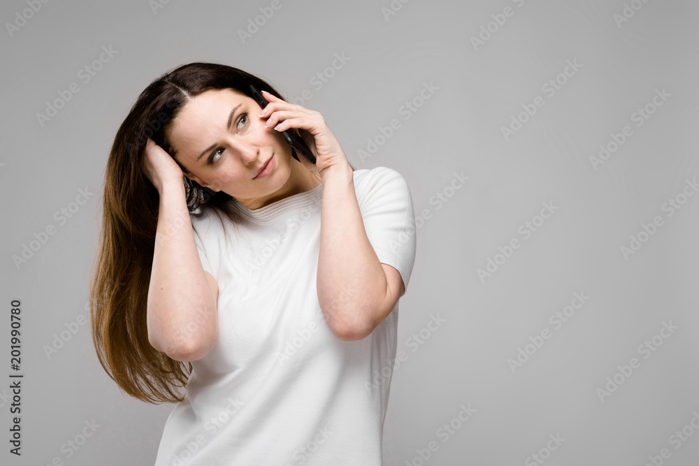 Emotional happy plus size model standing in studio looking in camera talking on phone with friend Emotional happy plus size model standing in studio looking in camera talking on phone with friend