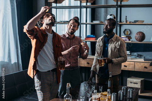 young multiethnic male friends drinking beer and partying together