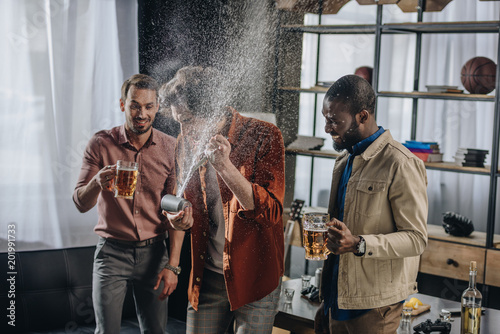 young male friends having fun together and drinking beer indoors