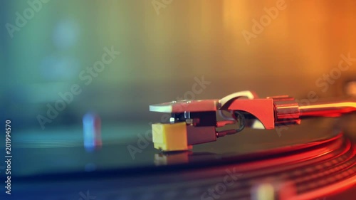 Slide defocus in focus. Vinyl player turntable. A fragment of the girl's hand stopping the stylus with the needle on a rotating black vinyl record close-up. Red and blue lights