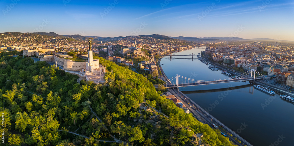 Naklejka premium Budapest, Hungary - Aerial panoramic skyline view of Budapest at sunrise. This view includes the Statue of Liberty, Elisabeth Bridge, Buda Castle Royal Palace and Szechenyi Chain Bridge with blue sky