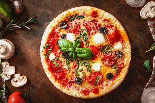 Hot pizza with Pepperoni with vegetables and fresh ingredients on rustic wooden table. 