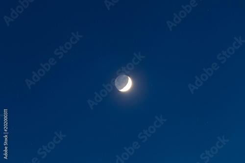 Moon - Waxing Crescent and grey light against blue starry sky background