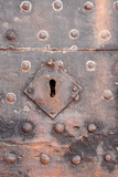 Very old iron keyhole on an iron door wiht studs and rust