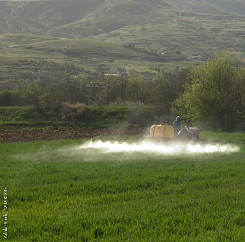 Farm tractor spraying pesticides at cultivation