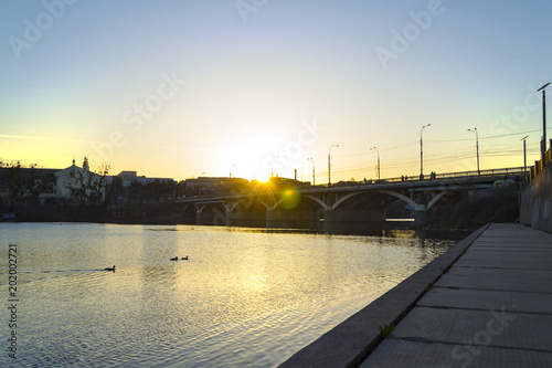 Fantastic colorful sunset in city on river with reflections and lens flare © Maksym Kapliuk