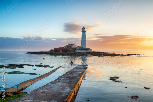 Kayakers paddle round the lighthouse at sunrise on St Mary's Island at Whitley Bay in Tyne and Wear on the Northumbria coast