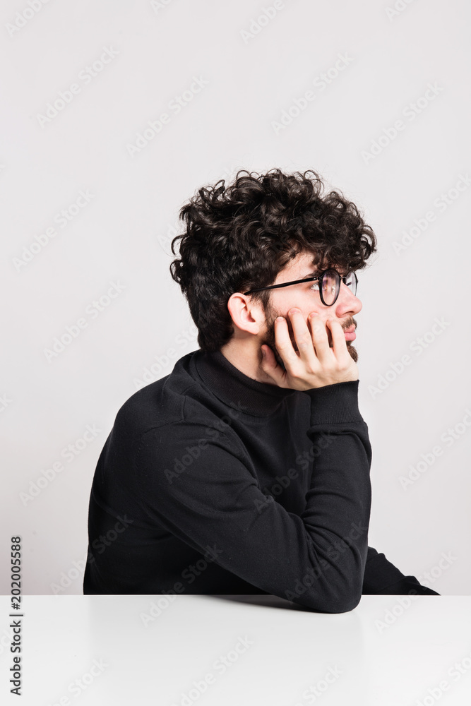 Young bored man in a studio, sitting at the table. Young bored man in a studio, sitting at the table.
