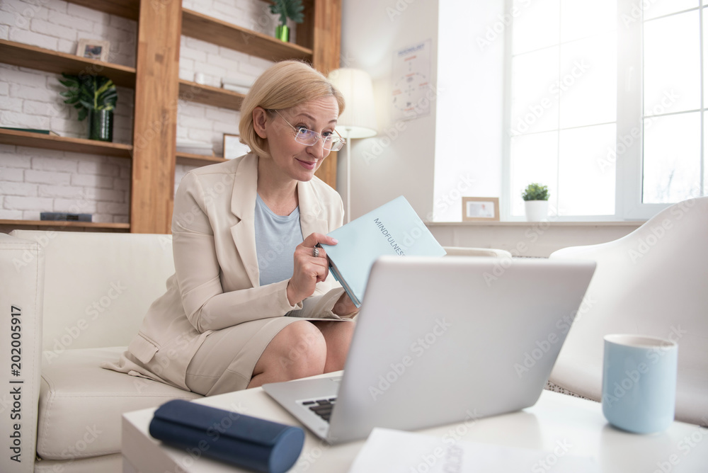My book. Successful mature businesswoman looking at screen while carrying book My book. Successful mature businesswoman looking at screen while carrying book