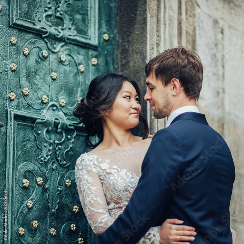 Elegant bride with groom walking near old catholic cathedral  © VAKSMANV