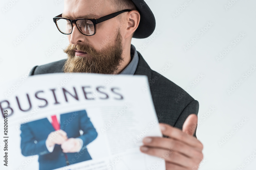 Stylish bearded businessman reading business newspaper isolated on light background Stylish bearded businessman reading business newspaper isolated on light background