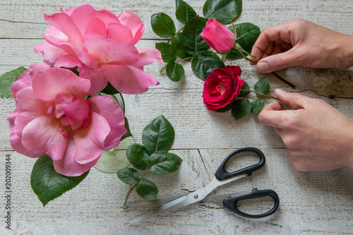 Top view of female decorator arranging roses on the wooden table, Concepts - fiorist, occupation, hobby, small business photo