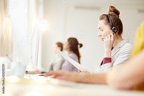 Businesswoman in headset communicating with client in call centre