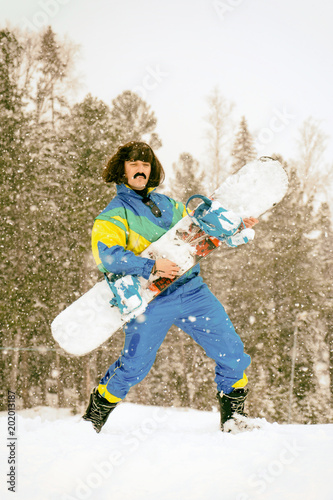 Vintage photo of young man snowboarder in the mountains. Retro style. 1980 concept.